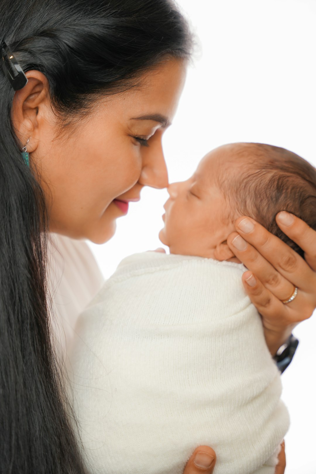 A mother holds her newborn close, smiling as their noses gently touch.